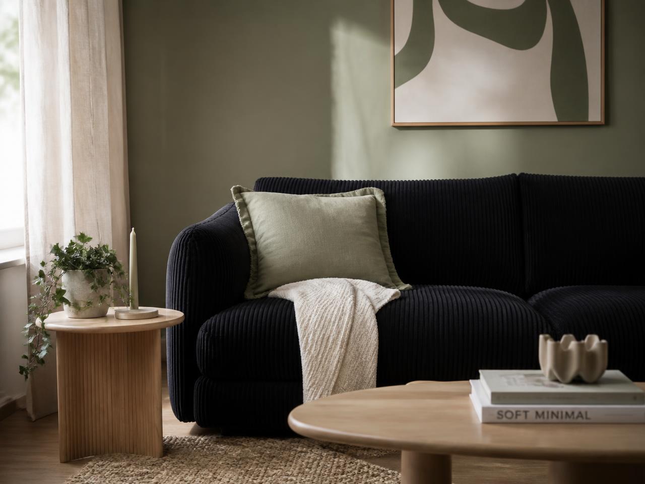 Wohnzimmer mit schwarzem Cordsofa und Holz-Beistelltisch